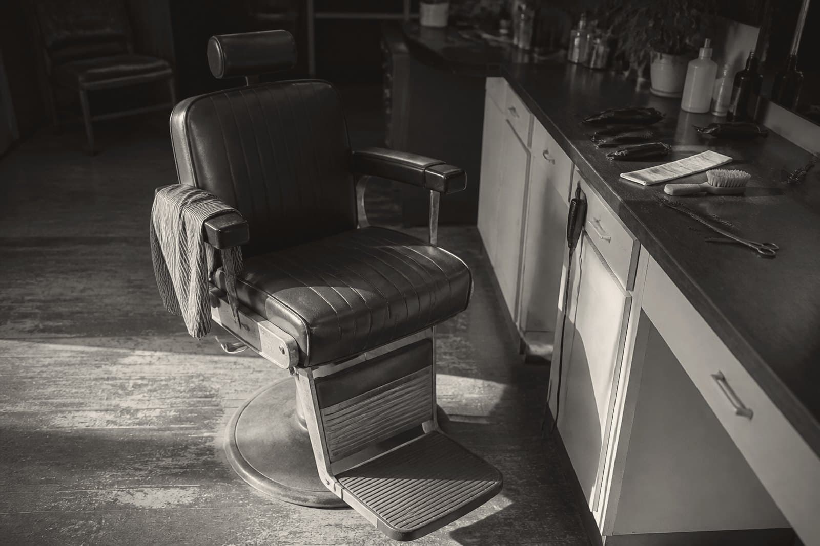 An empty barber chair between clients, tools left on the counter where they were put down